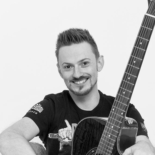 Chriss Lind, Portrait, schwarz-weiß, mit Gitarre, heller Hintergrund