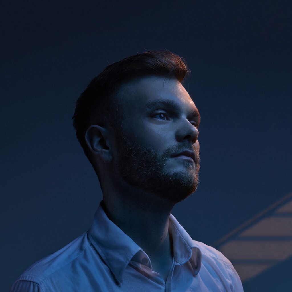 Michael Russ, blauer Hintergrund, dunkel, nachdenklicher Gesichtsausdruck