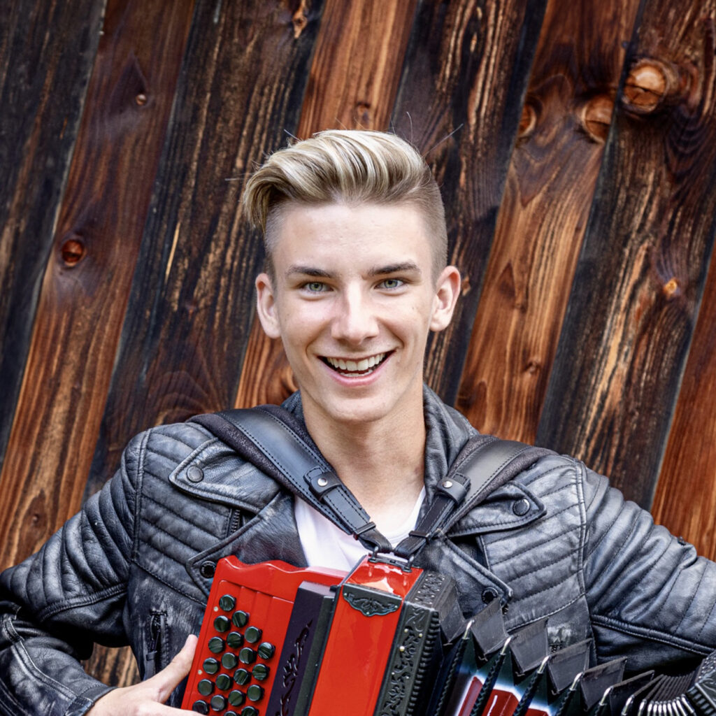 Felix Muhr, Steirische Harmonika, Lächeln, Holzwand